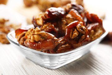 Walnut and date fruit in plate on wooden table, close-up