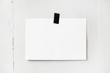 Blank white poster hanging on a tape on the wall. Template backg