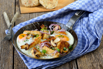 Deftiges Knödelgröstl mit Spiegeleiern und Schwammerl in der Eisenpfanne serviert
