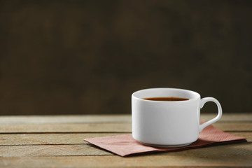 Cup of coffee and coffee grains on wooden table, on gray background