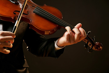 Musician plays violin on black background, close up