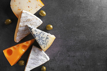 Different kinds of cheese, olives and rosemary on grey background, copy space