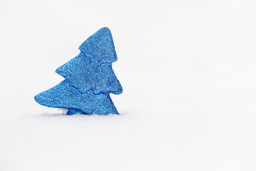 Minimalistic photo of blue toy tree on real snow at winter day.