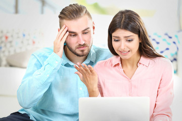 Happy couple sitting on the floor and working on laptop in a room