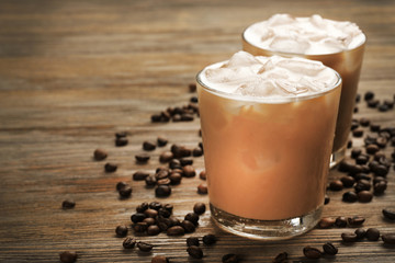 Two cups of ice coffee with coffee beans on wooden table