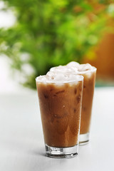 Cups of ice coffee on light blurred background