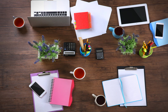 Session concept. Tablet, laptop, papers and cups of tea on wooden background. Top view.