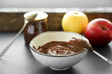 Melted chocolate in bowl, on wooden background