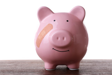 Piggy Bank with adhesive bandage wooden table, on white background