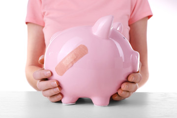 Woman holding Piggy Bank with adhesive bandage, on white background