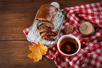 Cup of tea with autumn decor on wooden table.