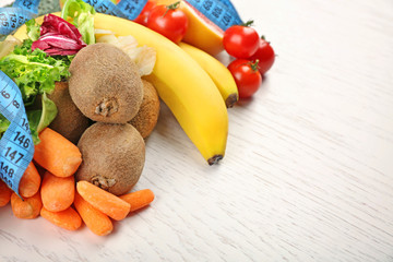 Fruits, vegetables and measuring tape on light wooden background. healthy eating concept.