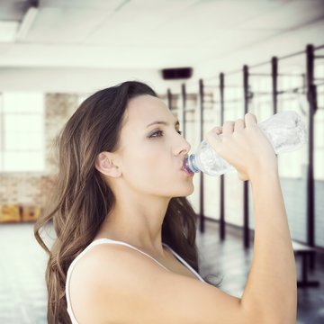 Composite image of beautiful woman drinking water from bottle