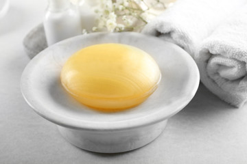 Soap on a dish with towels over beige background, close up