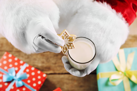 Christmas concept. Santa with glass of milk and cookies in hands, close up