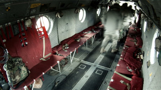 A soldiers come in the back hatch and sit on the red benches.