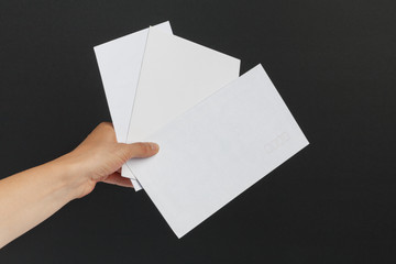 Female hand delivering 3 envelopes on black background