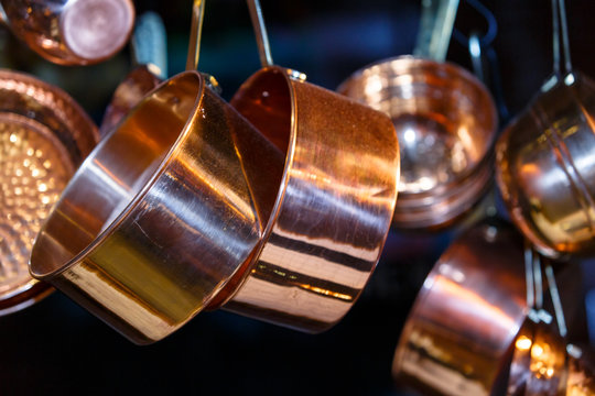 Copper pots and other utensils hanging on hooks from the ceiling