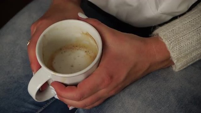 Woman holds coffee mug warming her hands closeup 4K