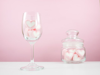 The lovely pink heart marshmallows in wine glass and small glass jar on white table for Valentine's day.