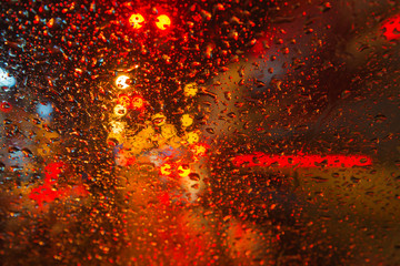 Rain drop with street colorful traffic lights at night blur bokeh abstract background 