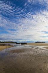 Stranded boats on a low tide beach and blue sky