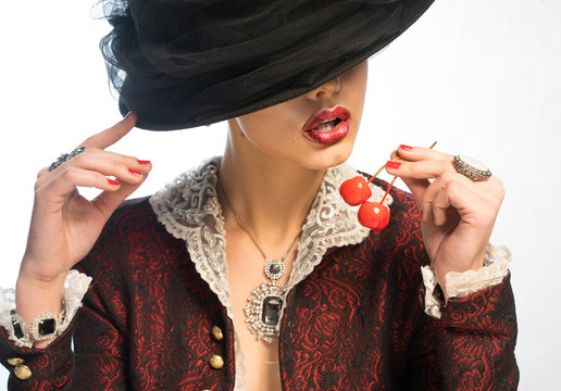 A woman in a vintage hat eating cherry