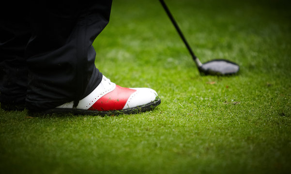 Golf player's legs on grass field.