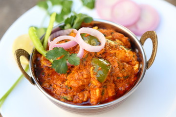 Butter chicken mutton curry or Indian style cottage cheese curry in a brass bowl with Salads.