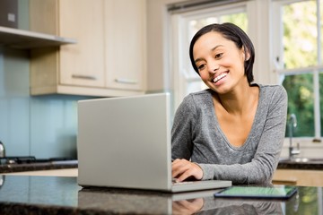 Smiling brunette using laptop