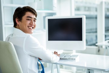 Smiling asian businessman using his computer