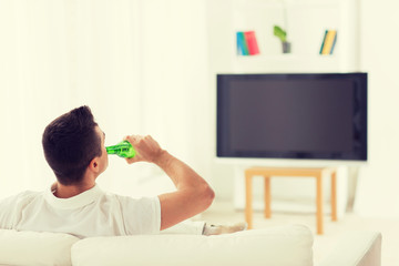 man watching tv and drinking beer at home