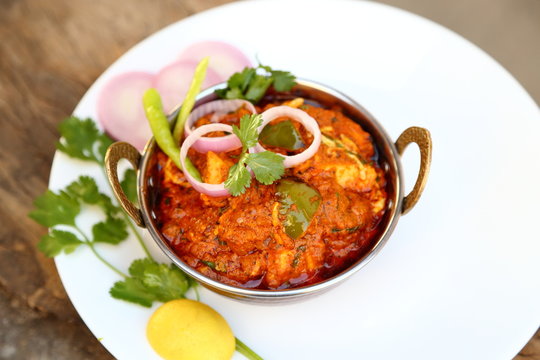 Butter chicken mutton curry or Indian style cottage cheese curry in a brass bowl with Salads.