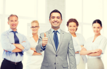 happy businessman in suit showing thumbs up