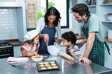 Happy family cooking biscuits together - obrazy, fototapety, plakaty