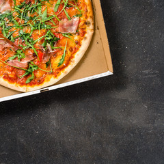 Italian pizza in cardboard box on dark background