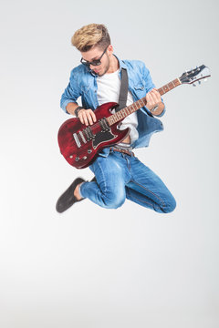 artist jumping in studio while playing guitar