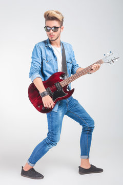 artist playing guitar in studio while posing looking away