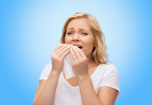 unhappy woman with paper napkin sneezing