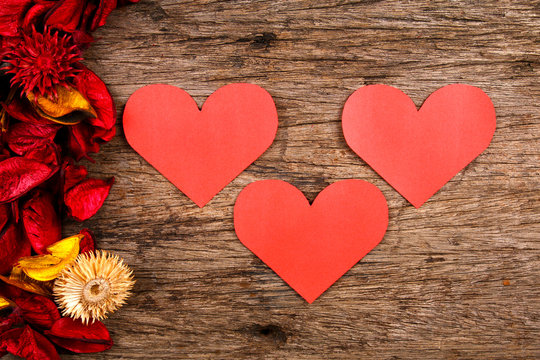 Hearts with red potpourri flower petals on wooden background