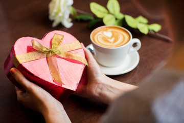 close up of hands holding heart shaped gift box