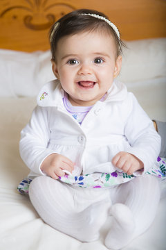 Bebé niña simpática sonriente sentada sobre una colcha de cama suave