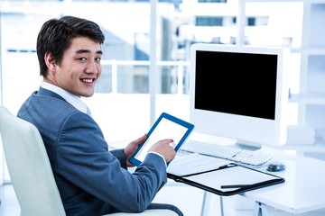 Smiling businessman using his tablet