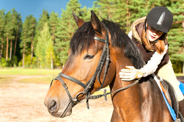 Obraz premium Girl equestrian riding horseback and stroking horse neck. Summer