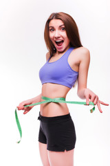 Fit and healthy young lady measuring her waist with a tape measure in centimeters and millimeters....