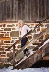 Obraz na płótnie Canvas Cheerful woman in white sweater on stairs of cosy mountain house