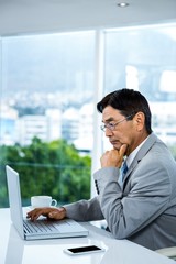 Thoughtful businessman using laptop