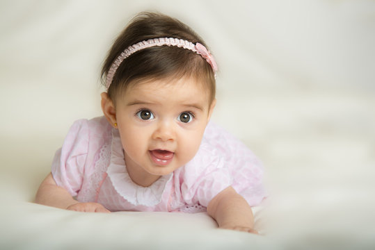 Beb&eacute; ni&ntilde;a con bonita sonrisa gateando por primera vez sobre una cama