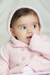 Beb&eacute; ni&ntilde;a simp&aacute;tica sonriente sentada sobre una colcha de cama suave