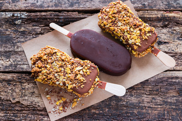 ice cream with chocolate and nuts on a paper on the wooden background